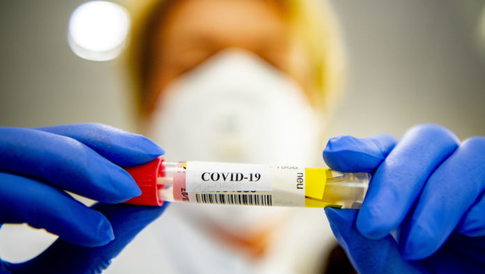 A lab technician holding a test tube that contains blood