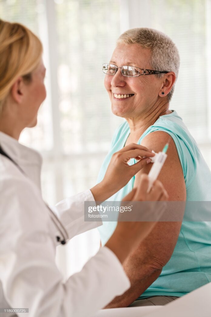 Senior woman receiving vaccine at the doctor's office.